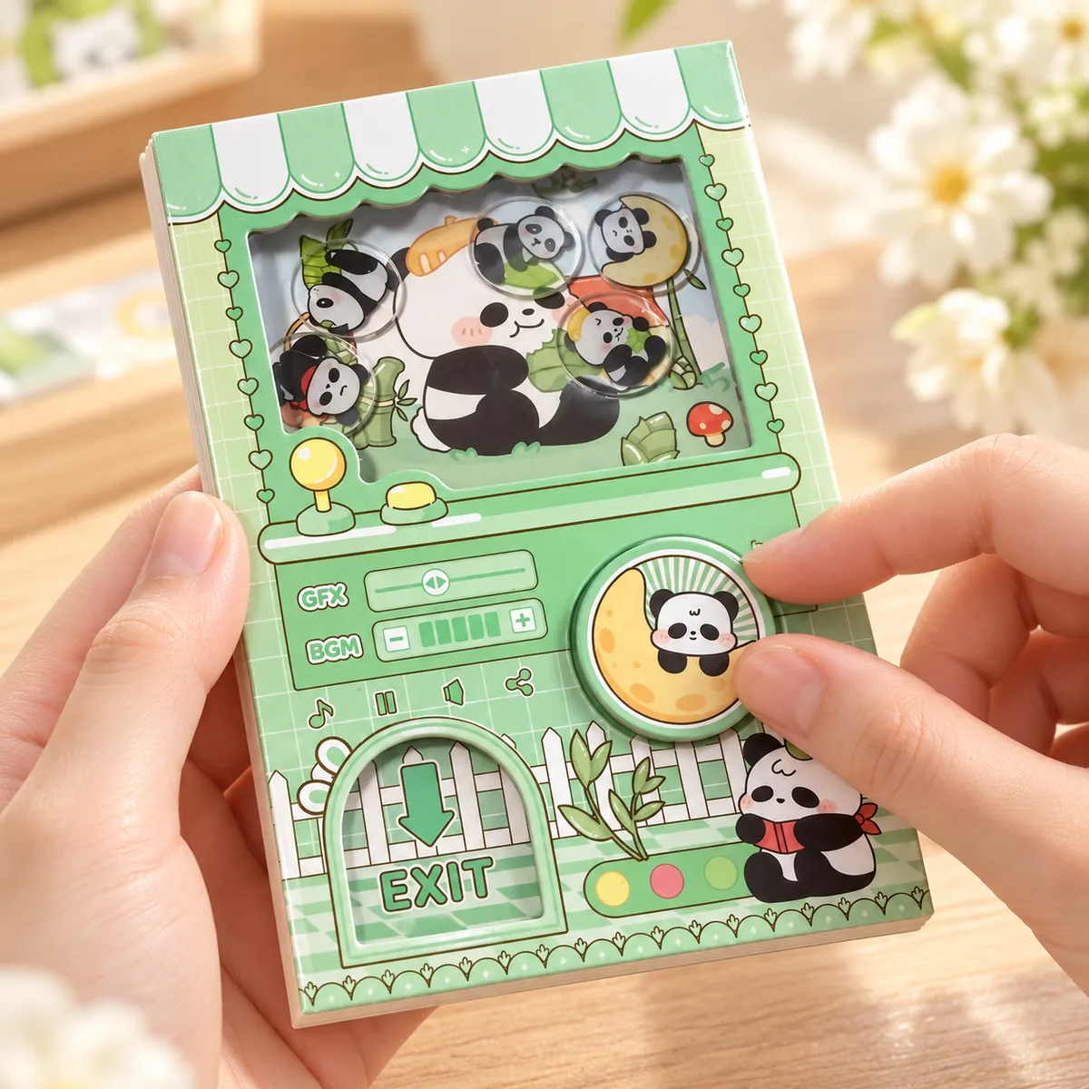 The green panda notebook held in both hands with a thumb turning the round dial on the front
