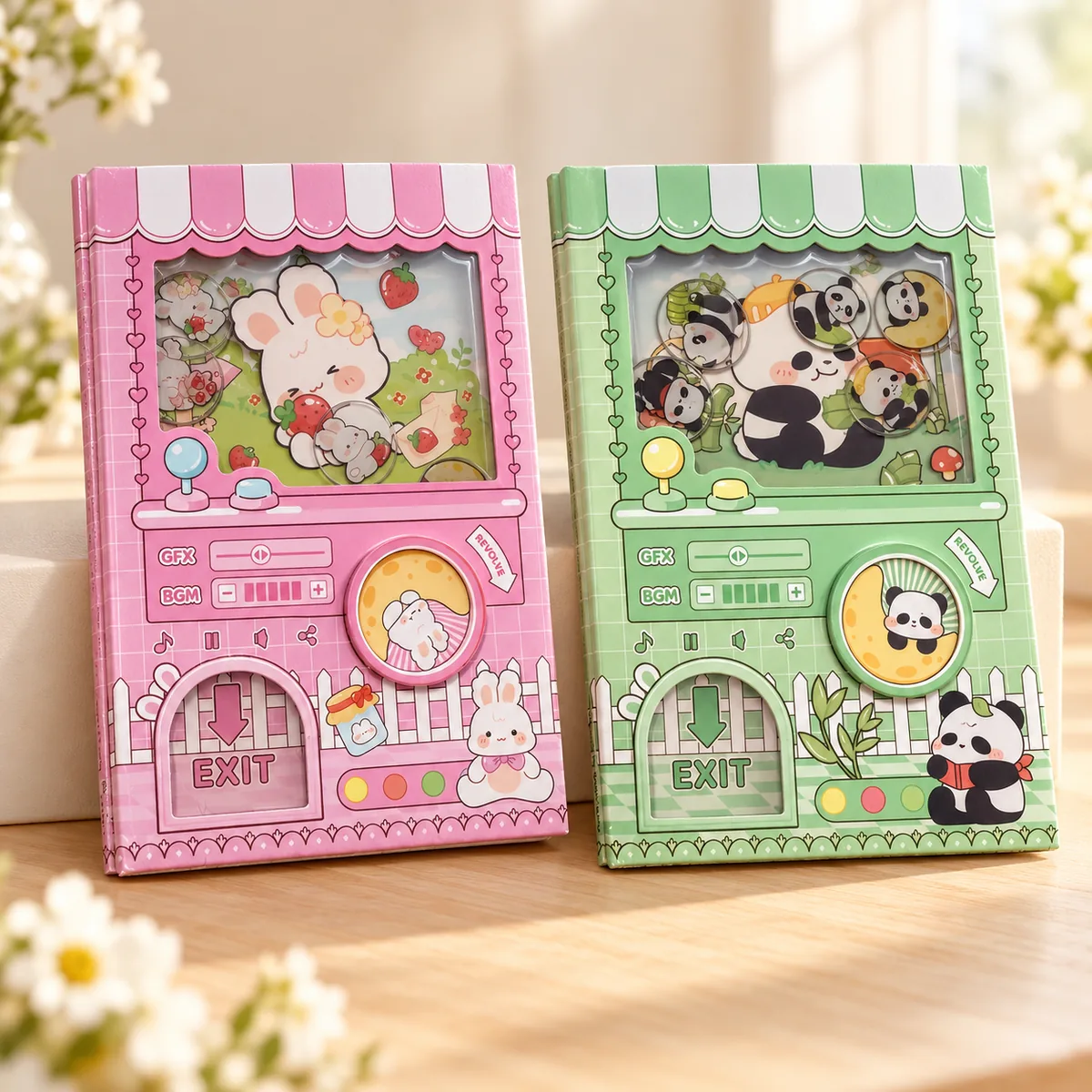 The pink bunny and green panda notebooks standing side by side, each cover styled as a little capsule machine with a striped awning, clear window and turn dial