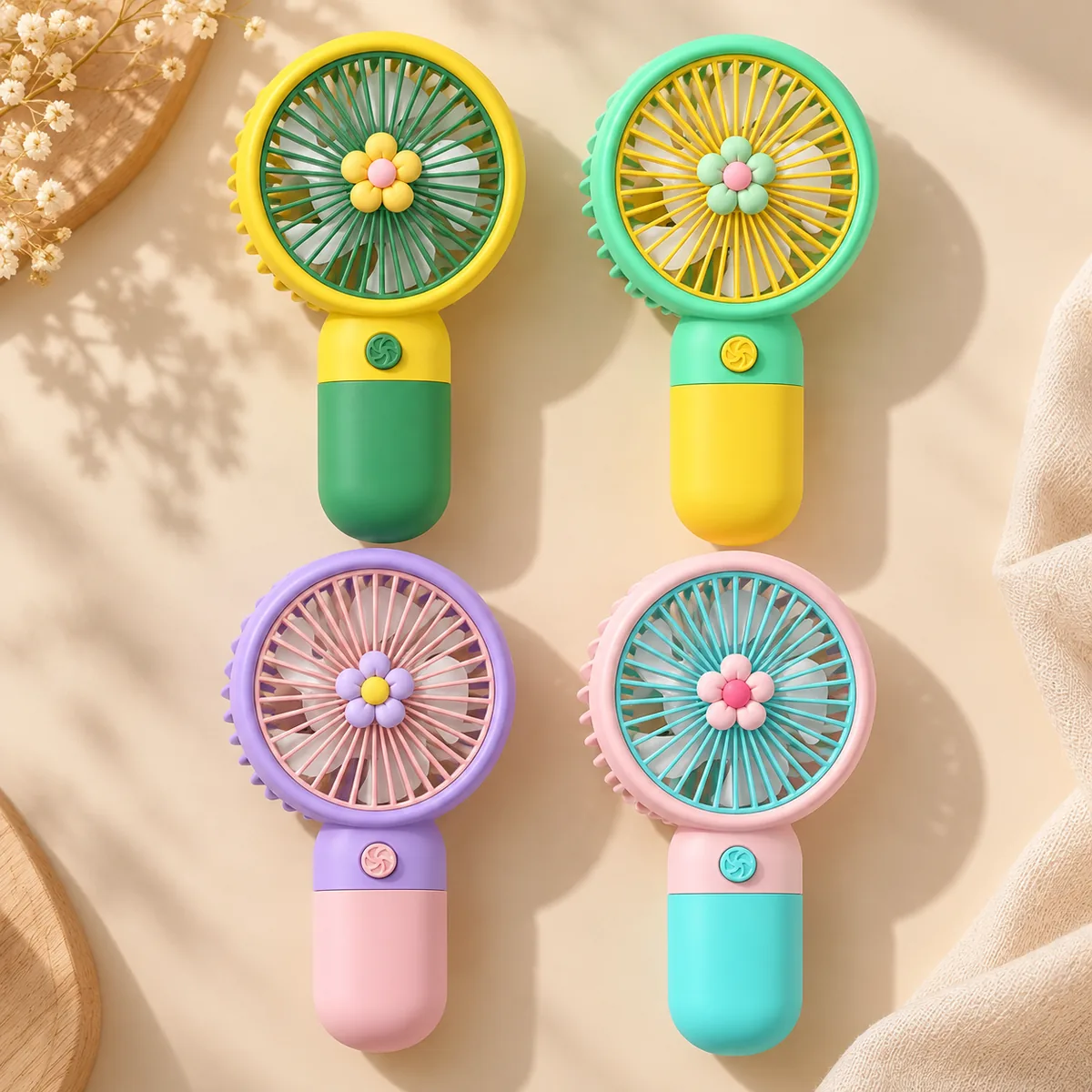 Four flower-design mini fans — yellow, mint, lilac and pink bodies, each with a moulded daisy charm at the centre of the blades