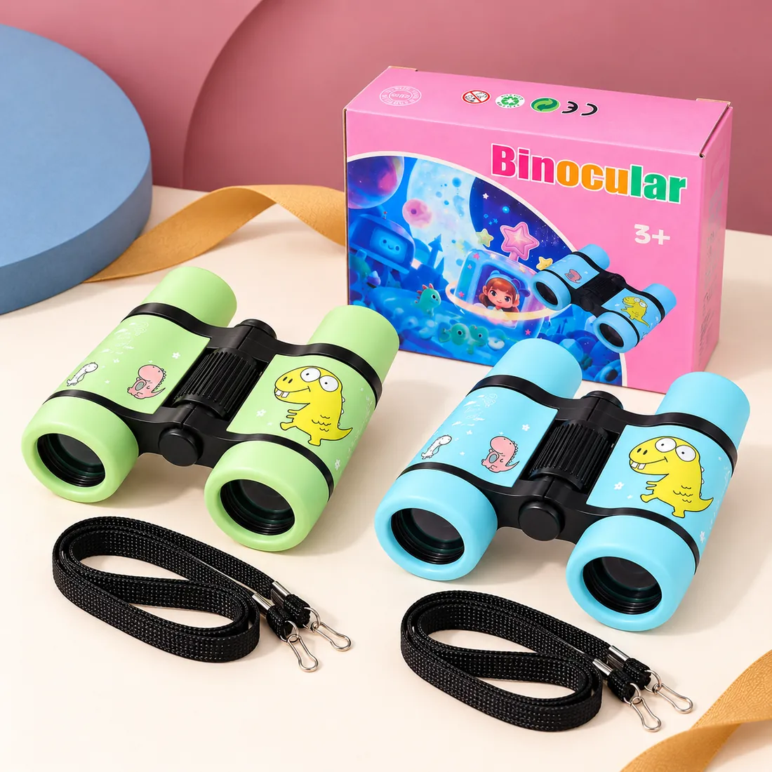The green and blue binoculars side by side with their neck straps and the printed box behind them