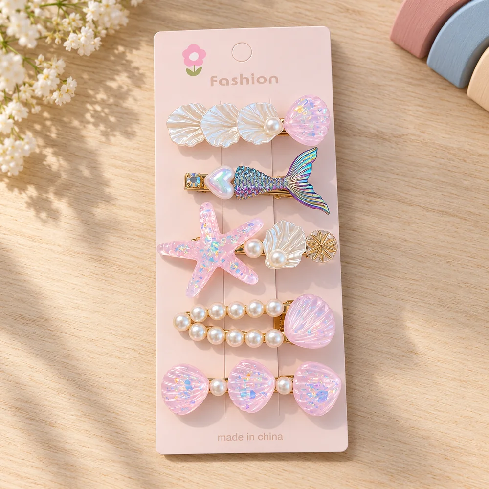 The pink card — five clips: a trio of white shells, a mermaid tail with a heart, a glittered pink starfish, a double row of pearls and three pink shells
