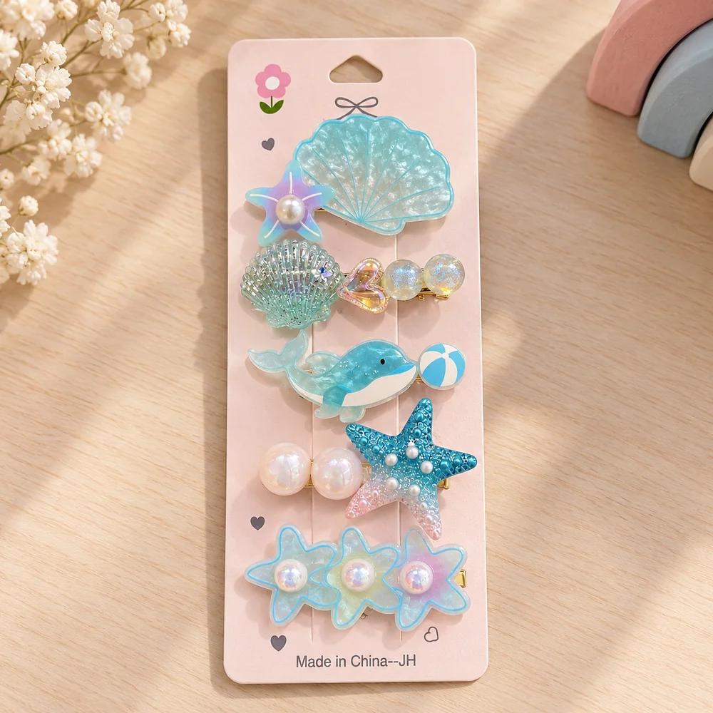 The aqua card — a large scalloped shell, a beaded shell, a dolphin with a beach ball, a blue starfish with pearls and a row of three starfish