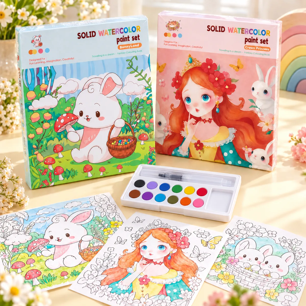 Both covers side by side — BunnyLand in blue and Crown Princess in pink — with the 12-colour solid watercolour tray, its water brush and three painted scenes laid out in front